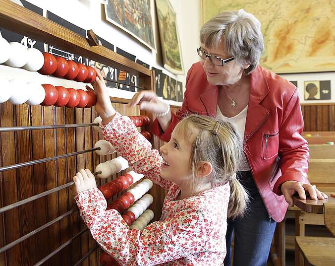 Ein Kind mit seiner Oma im alten Klassenzimmer