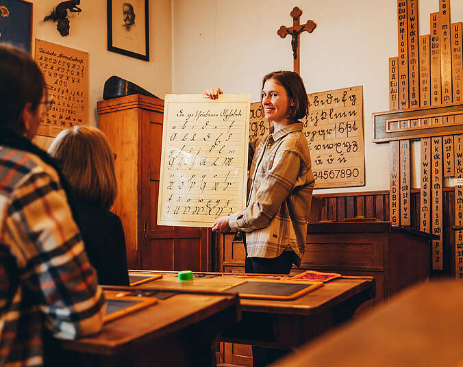 Eine Museumsführerin im historischen Klassenzimmer