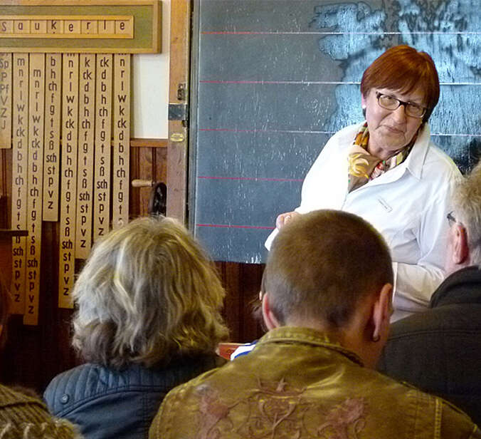 Frau erklärt etwas vor der alten Tafel