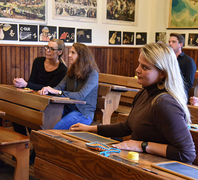 Erwachsene sitzen in altem Klassenzimmer