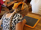 Ein Mädchen mit einem Kopftuch schreibt auf einer Schiefertafel
