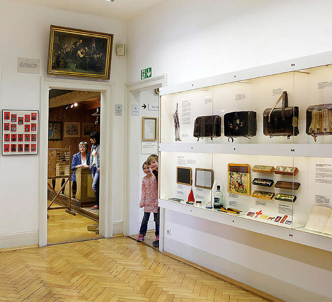 Vitrinen mit alten Schultaschen, Schreibuntensilien und Tinte