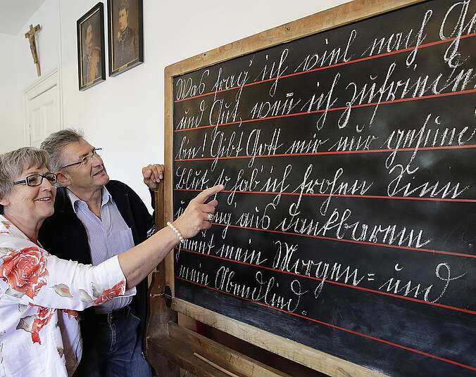 ZWei Senioren betrachten eine Tafel mit alter Schrift
