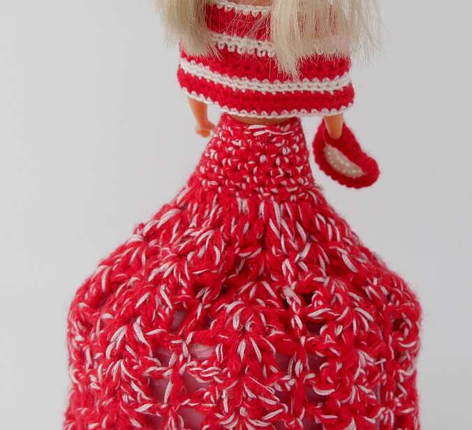 Die Rückansicht der Barbiepuppe in einem roten Kleid. Unter ihrem Rock ist eine Rolle Klopapier.