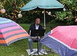 Ein Mann sitzt unter einem Regenschirm und liest vor