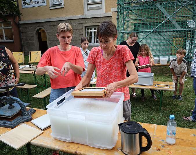 Zwei Frauen beim Papierschöpfen