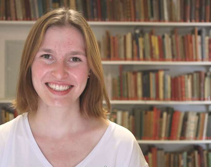 Mitarbeiterin Karin Oelfke vor einem Bücherregal