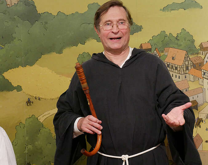 Ein Mann ist als Mönch verkleidet und erzählt etwas
