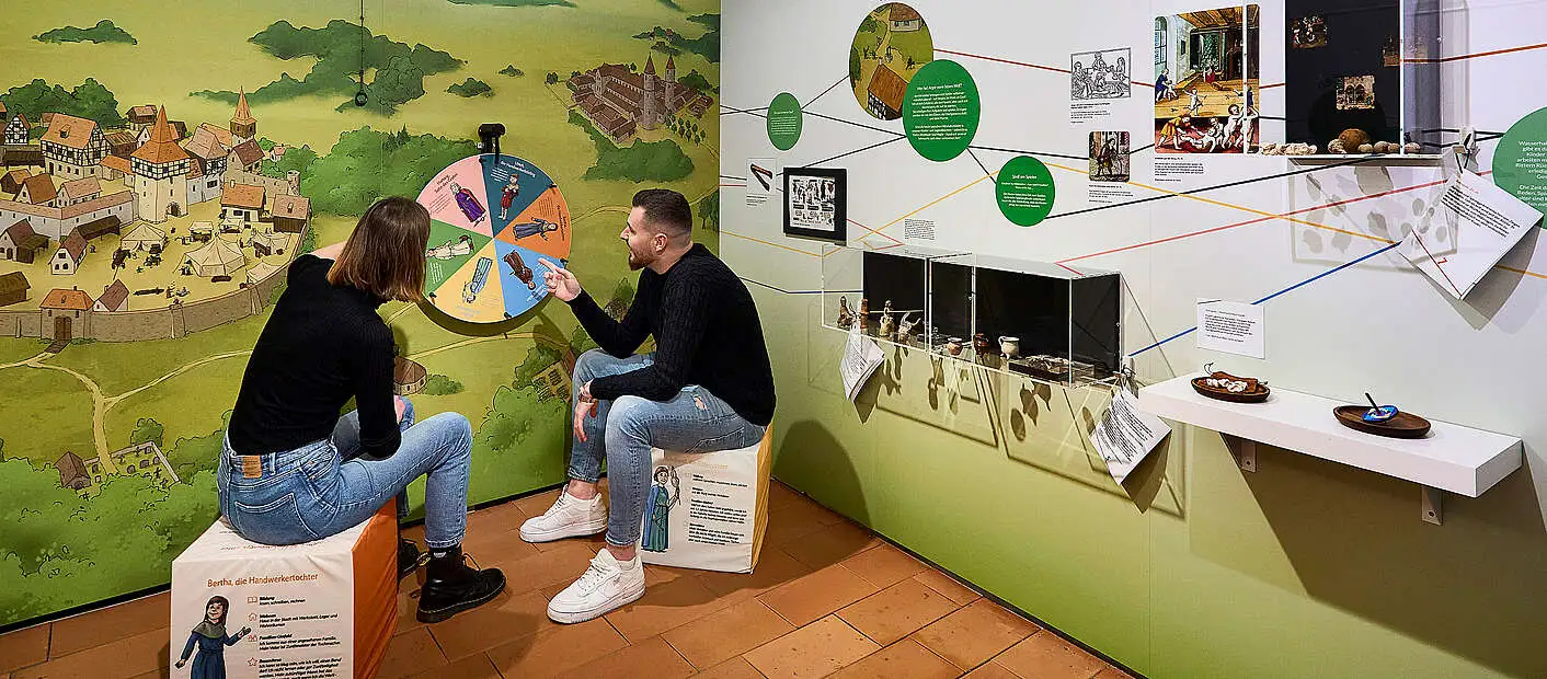 Zwei Menschen sitzen in einer Ausstellung
