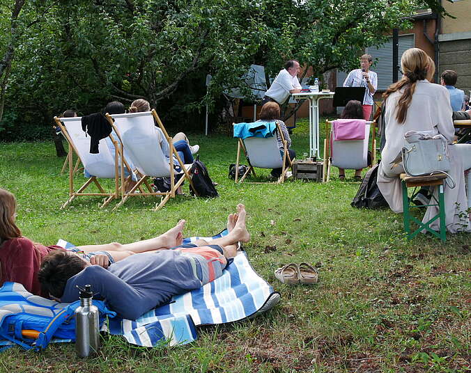 Menschen liegen auf einer Picknickdecke im Garten