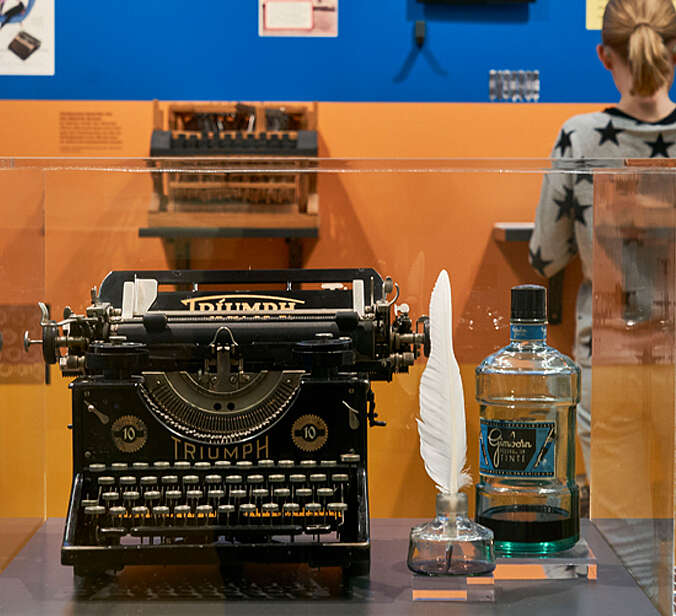 Schreibmaschine, Feder und Tinte in Vitrine