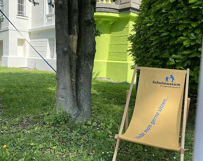 Ein gelber Liegestuhl steht vor der grünen Fassade des Museums.