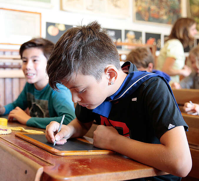 Jungen schreiben auf Schiefertafel